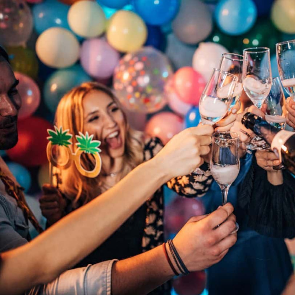 Toast lampkami szampana na tle kolorowych balonów podczas prywatnego przyjęcia