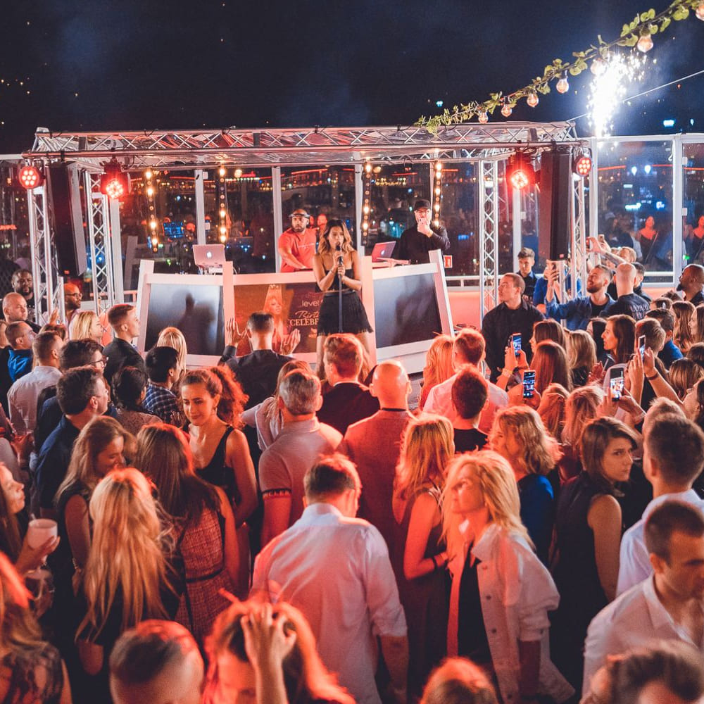 Tłum bawiący się na imprezie na dachu z DJ-em na scenie